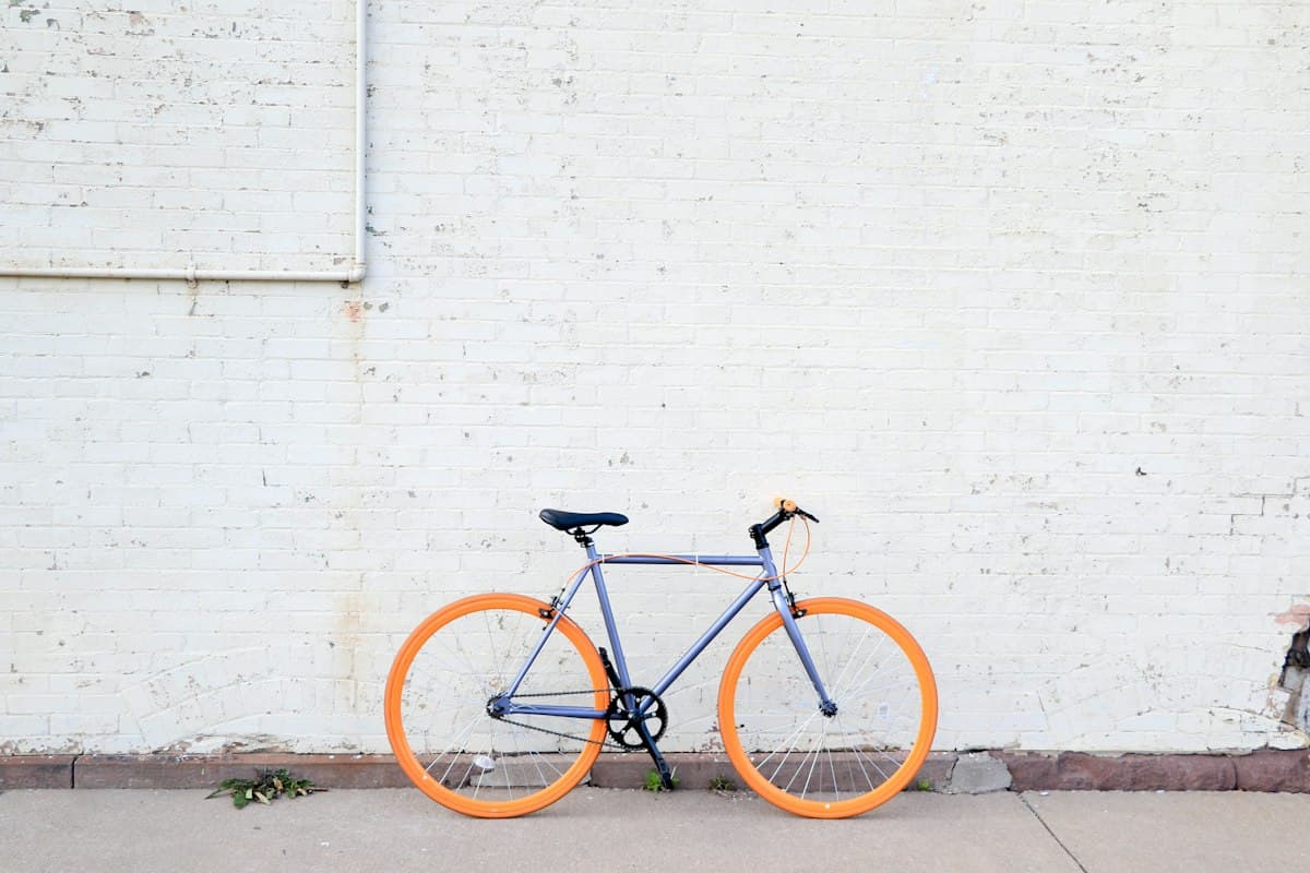 Vélo aux roues orange contre un mur blanc