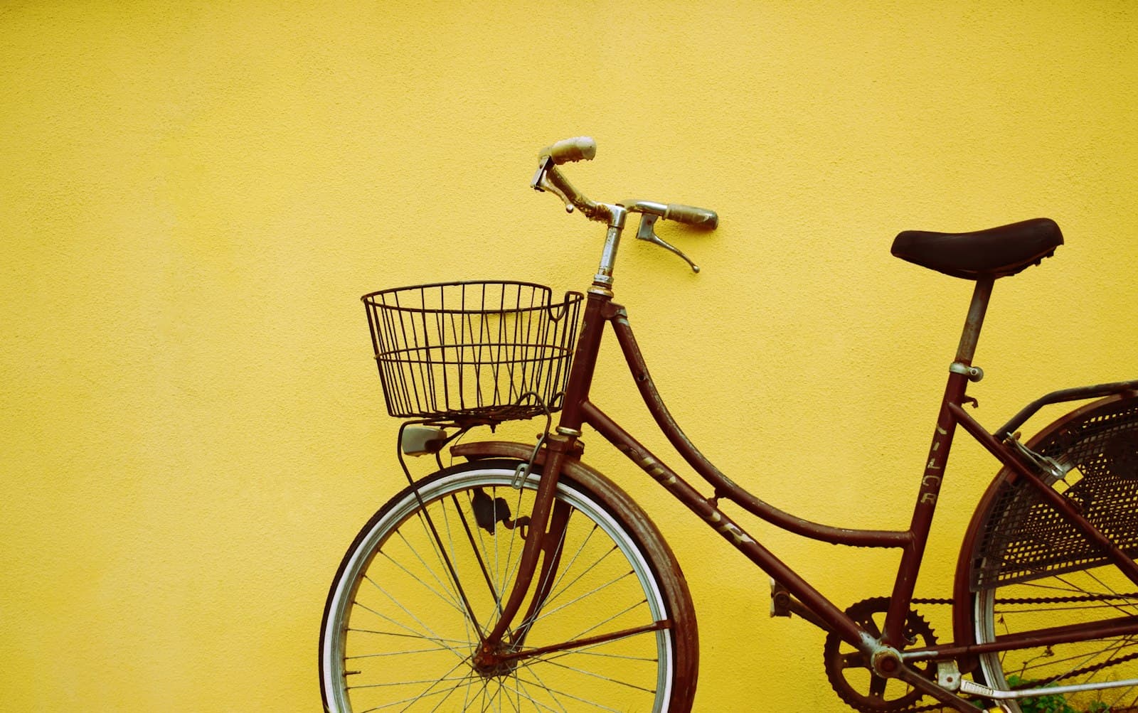 Vélo de ville avec panier contre un mur jaune